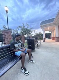 a young man sitting on a bench at dusk